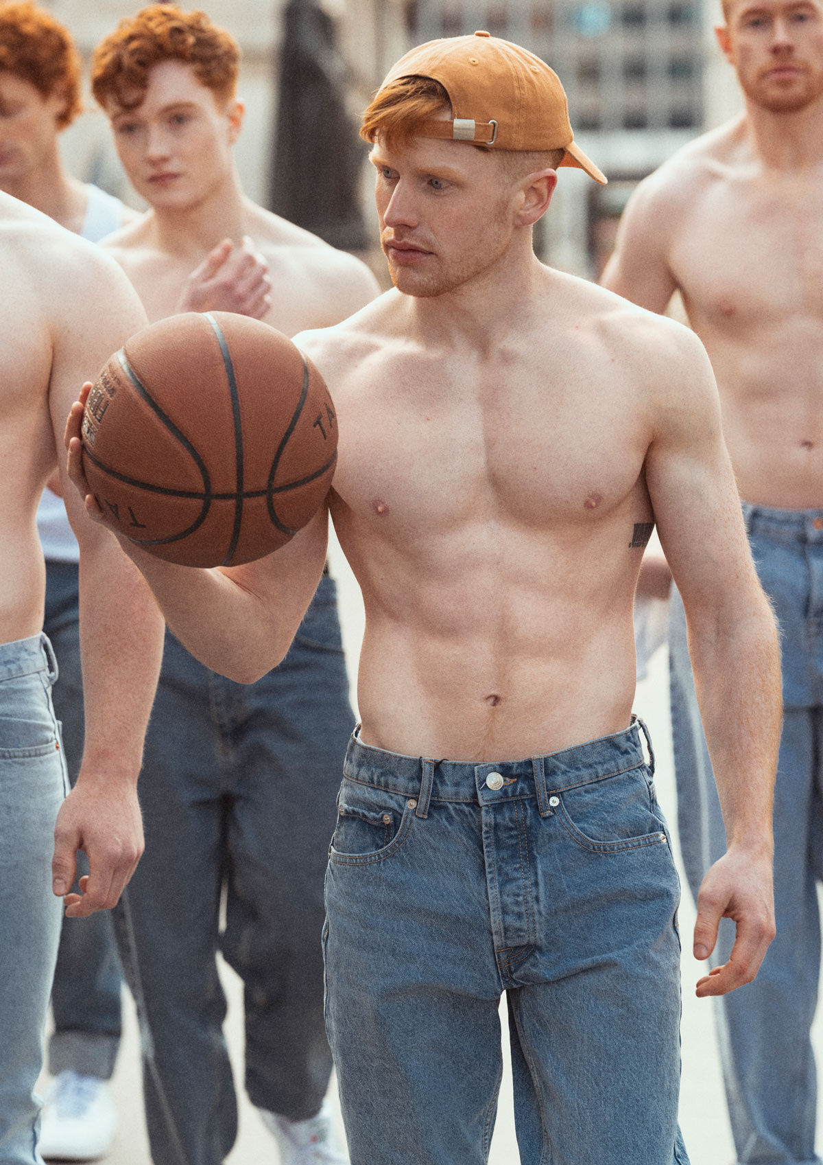 Coach is holding a basketball, shirtless, wearing a baseball cap.